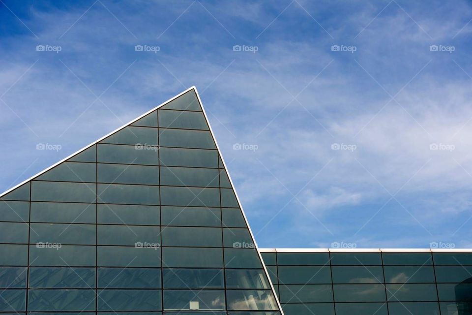 Abstract geometrical capture of a glass structure with the cloudy sky in the background 