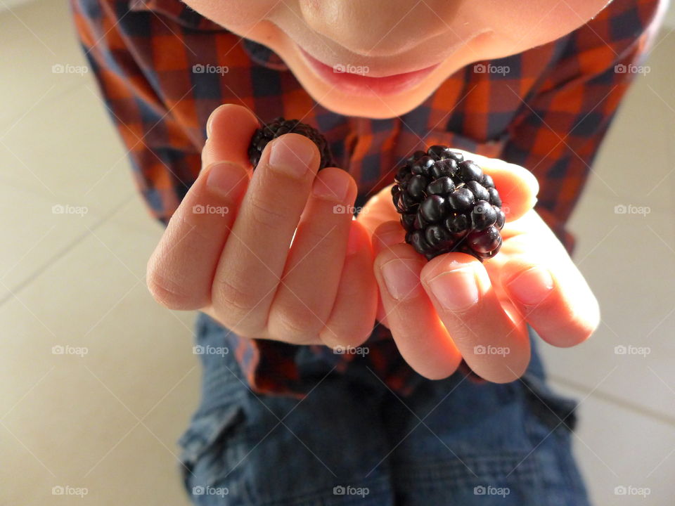 child bringing blackberries close to lips