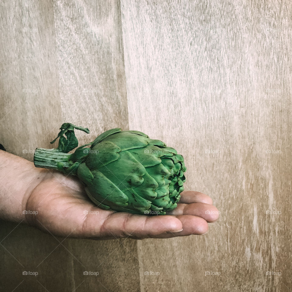 Hand holding artichokes