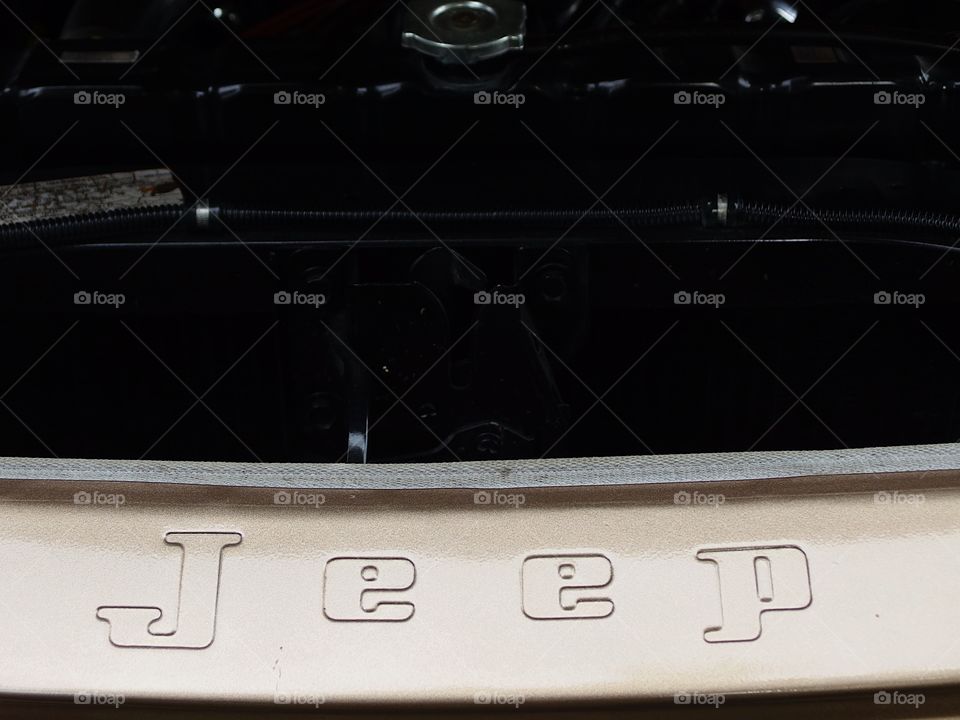 The rugged logo on a raised hood of a classic brown Jeep Commando at the annual car show in Drake Park in Central Oregon during the summer. 