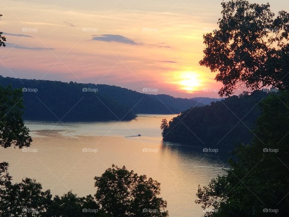 Magnificent colors of vibrancy as the glowing sun sets over tranquil waters of Normandy Lake in the evening.