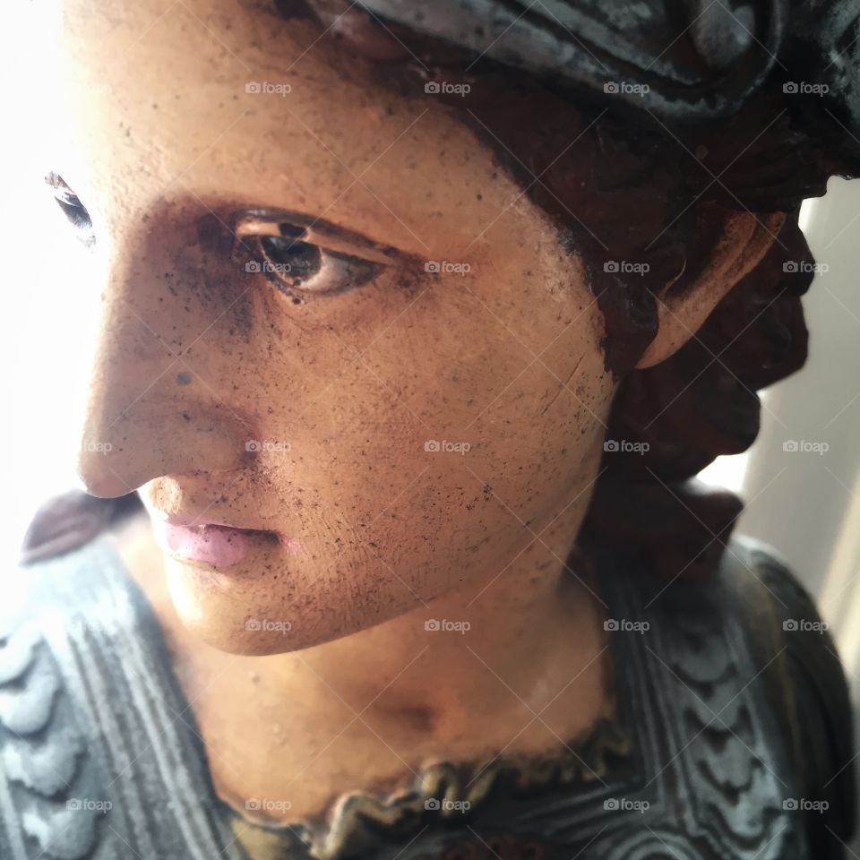 A bust of the goddess Pallas Athena close up. She gazes to the left size, focused off the image, and is dressed in armor.