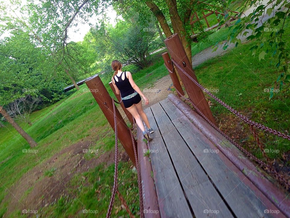 Sharing a walk with daughter. Teen walking across a walking path bridge