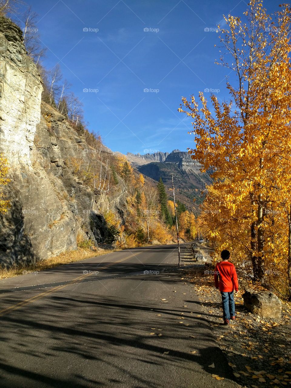 A boy walking down  road at Glacier National Park, MT in the Fall