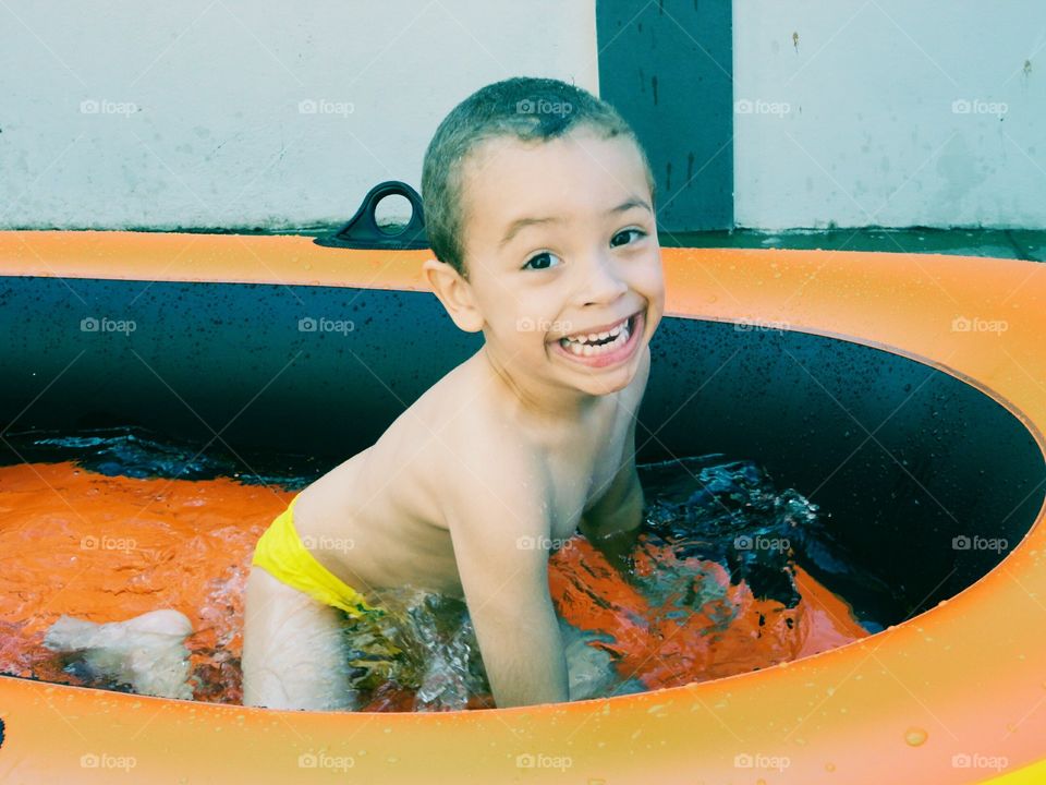 Smiling boy playing in inflatable tub