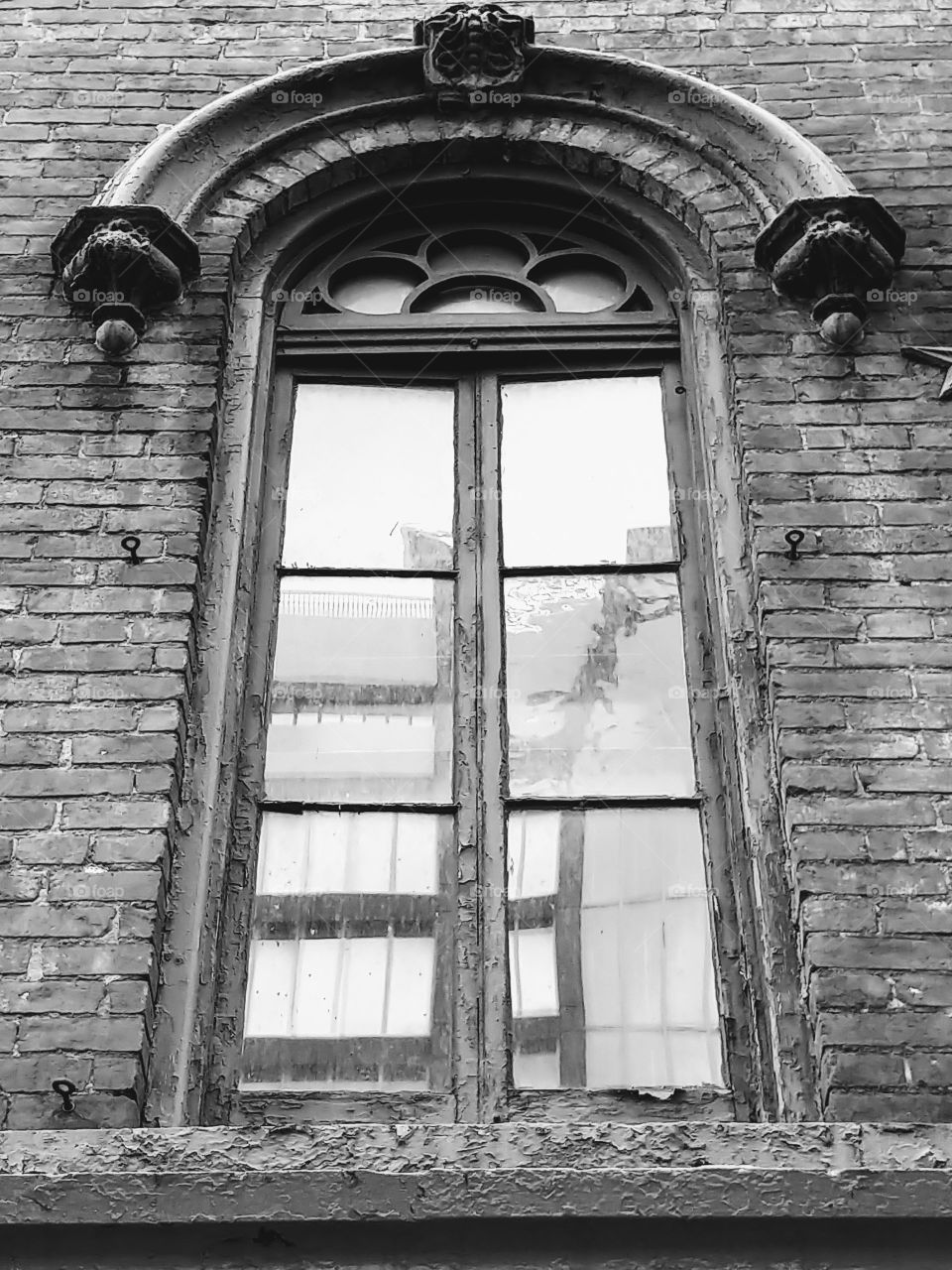 A black and white close up of a vintage window that shows the original wavey glass
