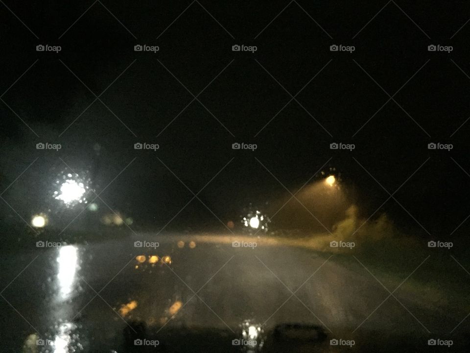 Rainy road in Florida, reflecting headlights with streetlight.