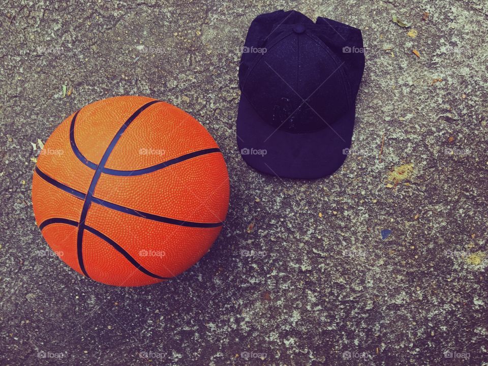 A basketball and a black cap thrown on the floor