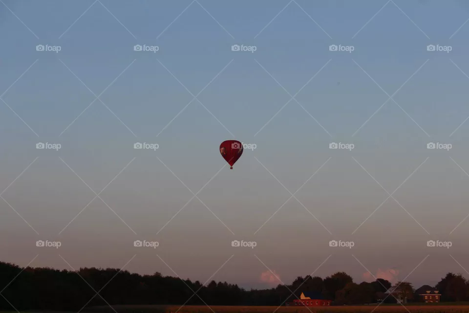 Hot air balloon high in the sky, above the meadows