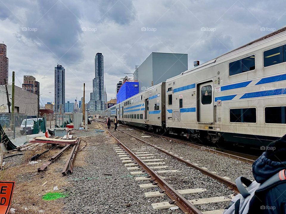 This is a train of the „Long Island Railroad“ passing us by on „11th Street“ and „Borden Avenue“ underneath the „Pulaski Bridge“ at „Newtown Creek“ in LIC, Queens on an overcast afternoon in December 2023. Hypnotic Productions
