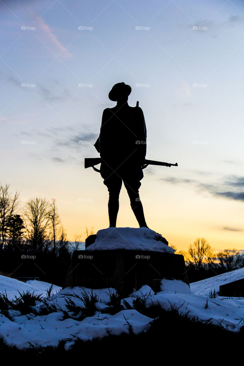 Silhouette of the statue of a soldier holding a rifle. The picture was shot at golden hour! Memorial, war, sunset related picture.