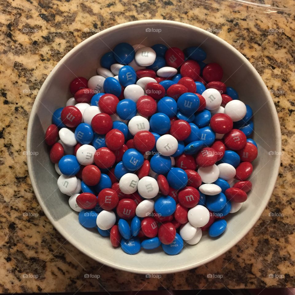 Overhead picture of red, white, and blue M&Ms in a white bowl.