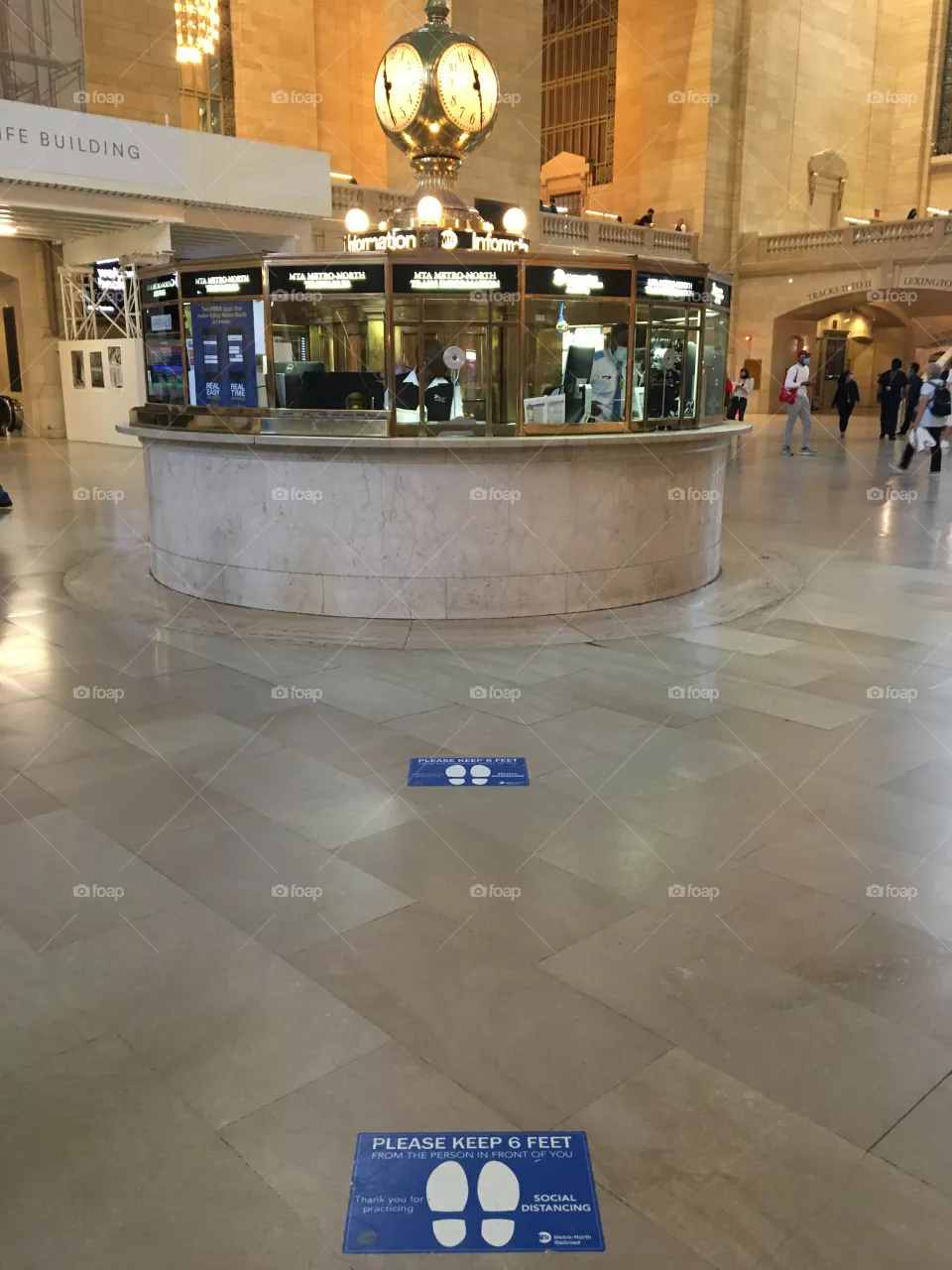 Quiet main hub at Grand Central Terminal in New York City in May (2021) with shoeprint signs on floor asking “please keep 6 feet” apart 