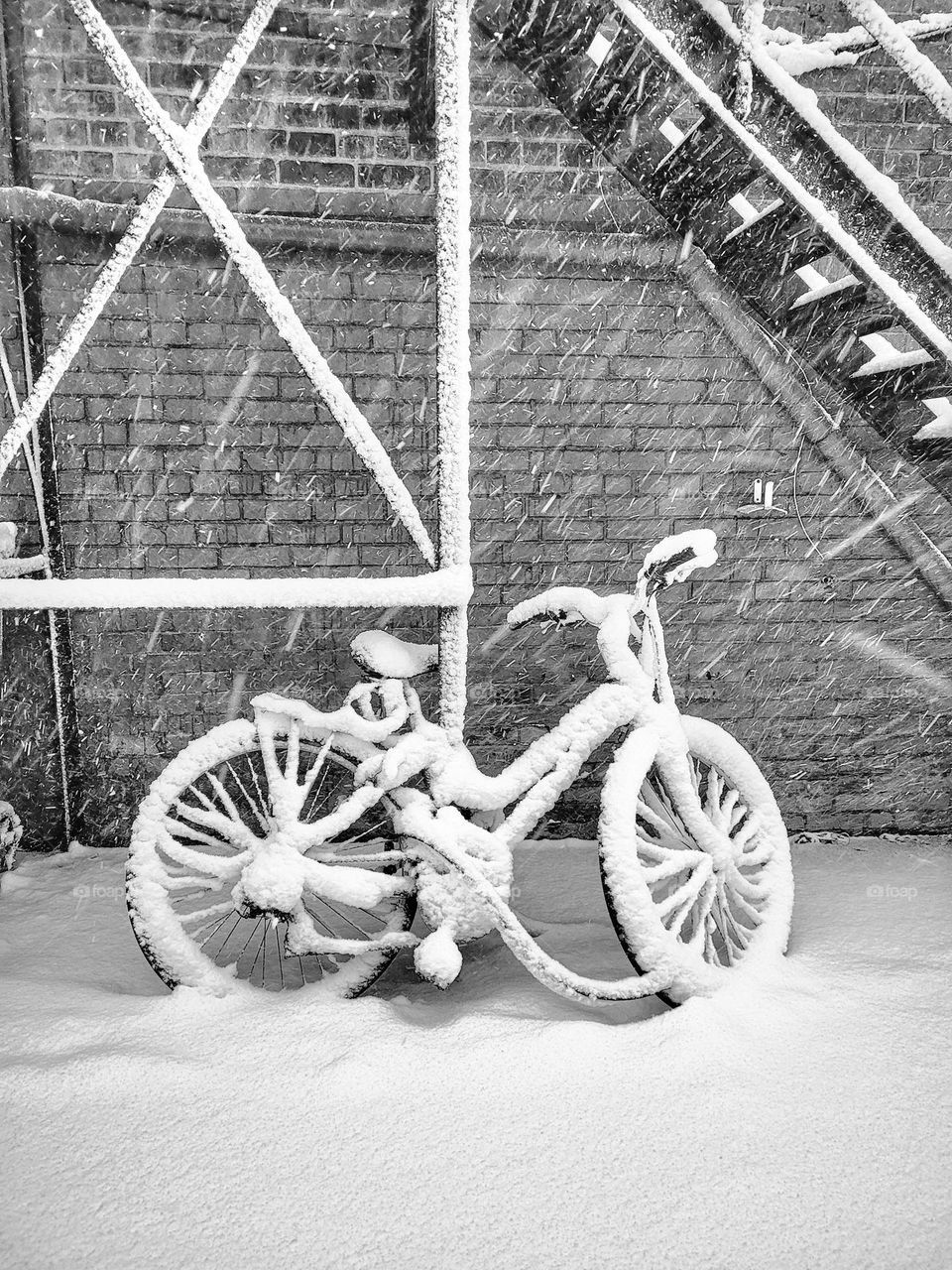 Lonely bicycle standing outside in city street in snowfall.  Winter landscape.