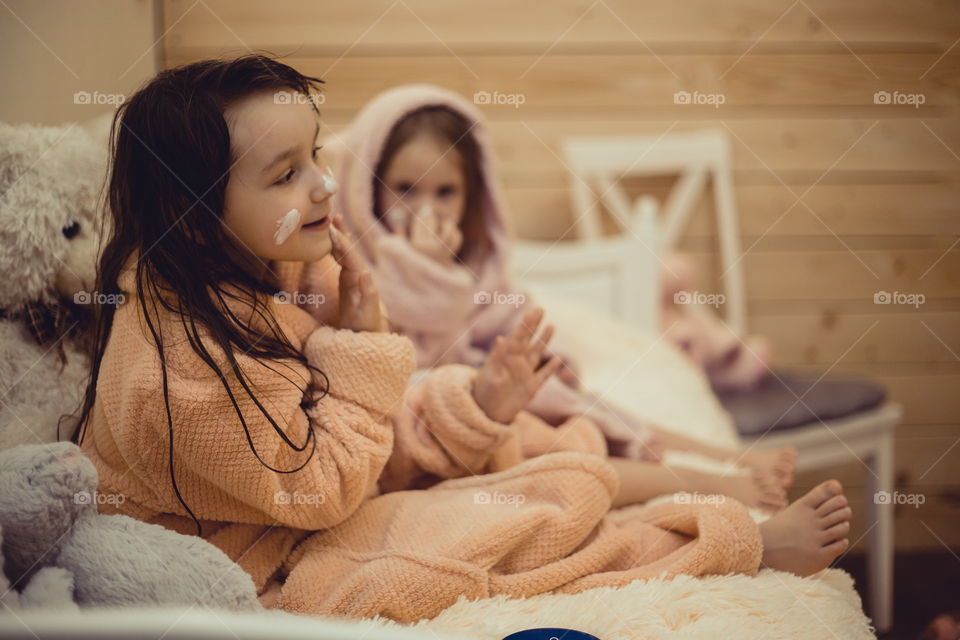 Little sisters in bathrobe with cream