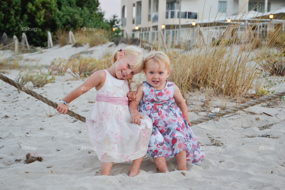 Two blonde sister sitting on rope