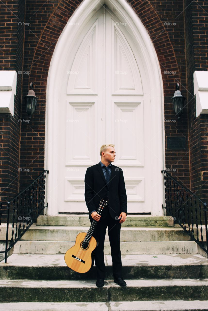 Classical guitarist portrait with historic church vibes to contrast and complement each other 