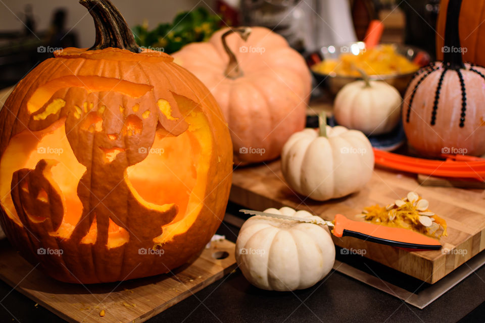 Pumpkin carving decorative Halloween cute dog Jack o’lantern carved pumpkin on preparation table indoors with pumpkin carving tools, white pumpkins, pumpkin seeds 