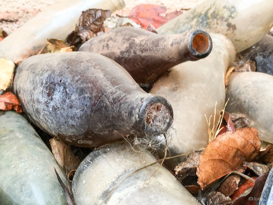 Old Amber antique bottle on its side muddy dirty filled with cobwebs 