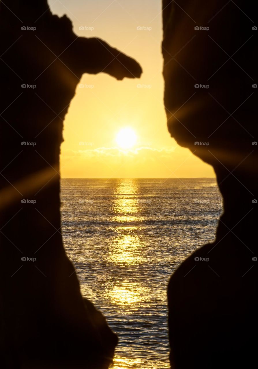 Sunrise over the sea viewed through old, rotting wooden sea defences 