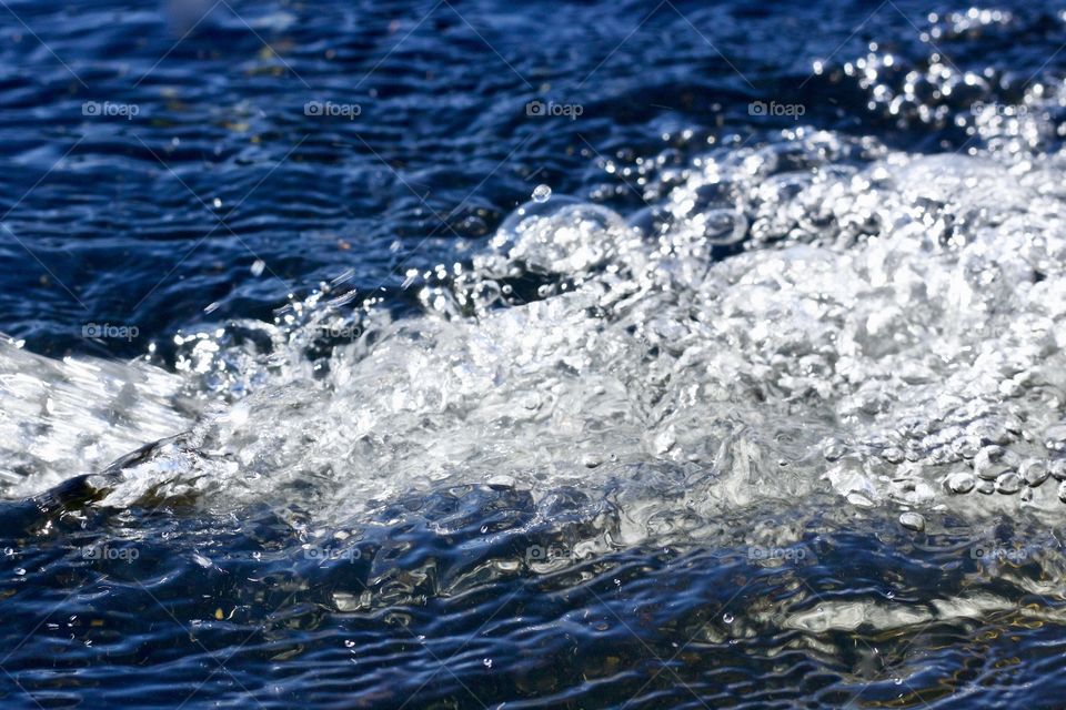 Isolated view of water splashing, reflecting a deep blue sky
