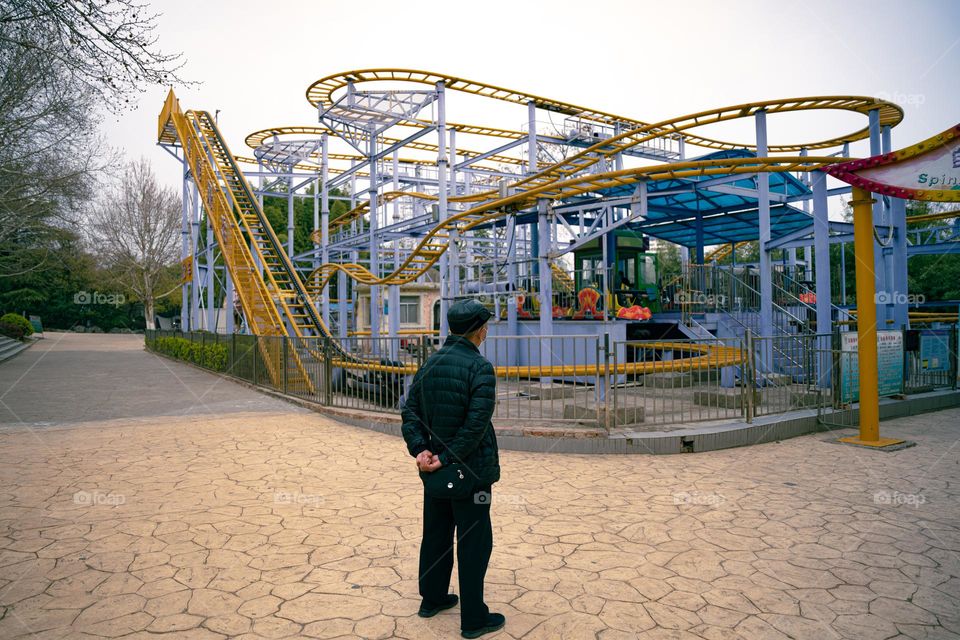 A man is looking at the roller coaster to remember his fun time .