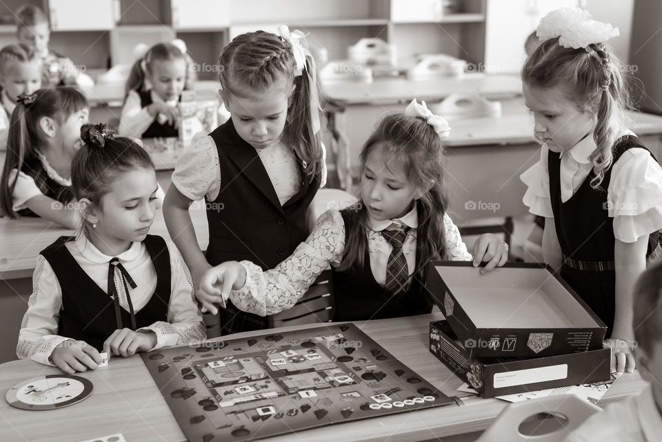 black and white photo girls first grade sitting at a desk at school playing a board game