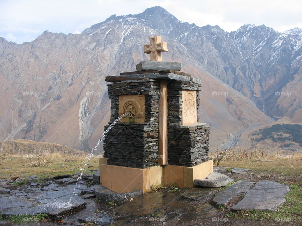water fountain in Kazbegi, Georgia with the Caucasus mountain range on the background.