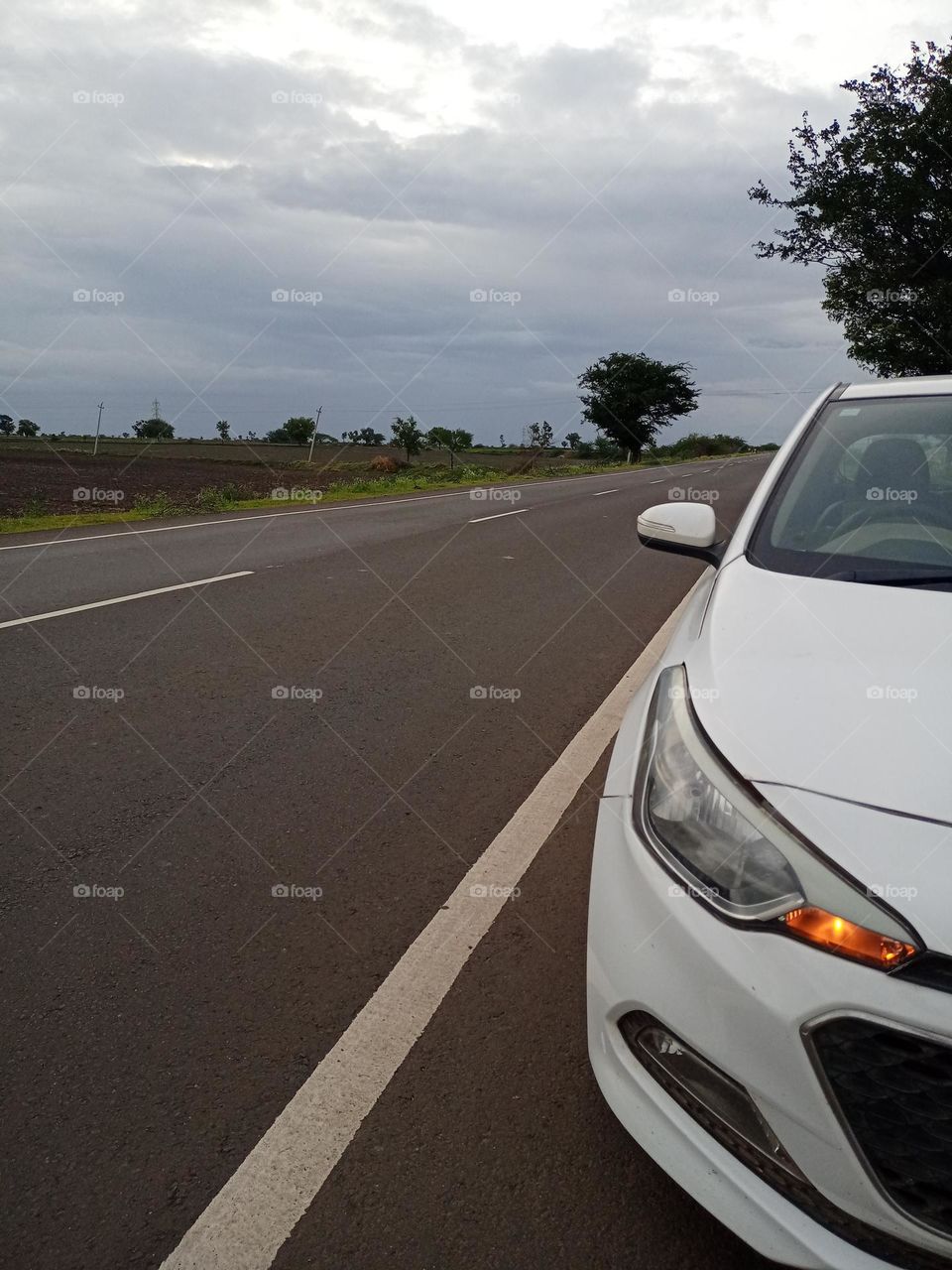 white colour car parking on the road side in evening time beutiful background with nice Cline road blue sky trees beauty of nature