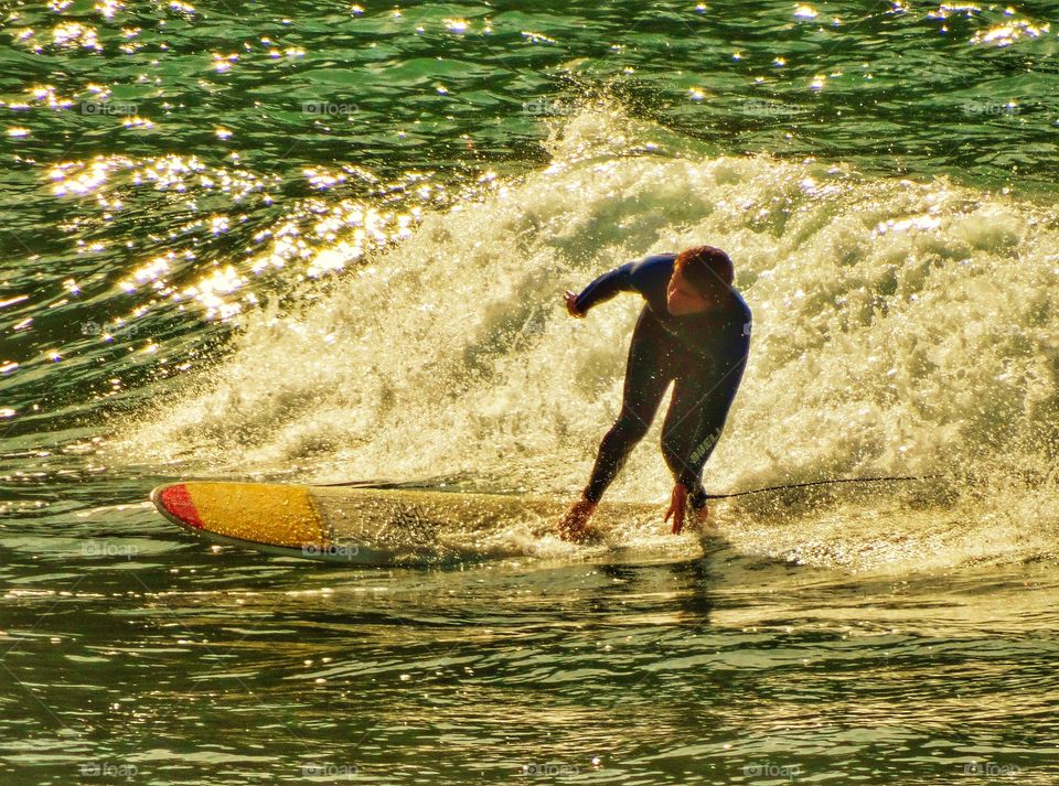 Surfing At Sunset. Surfer During The Golden Hour
