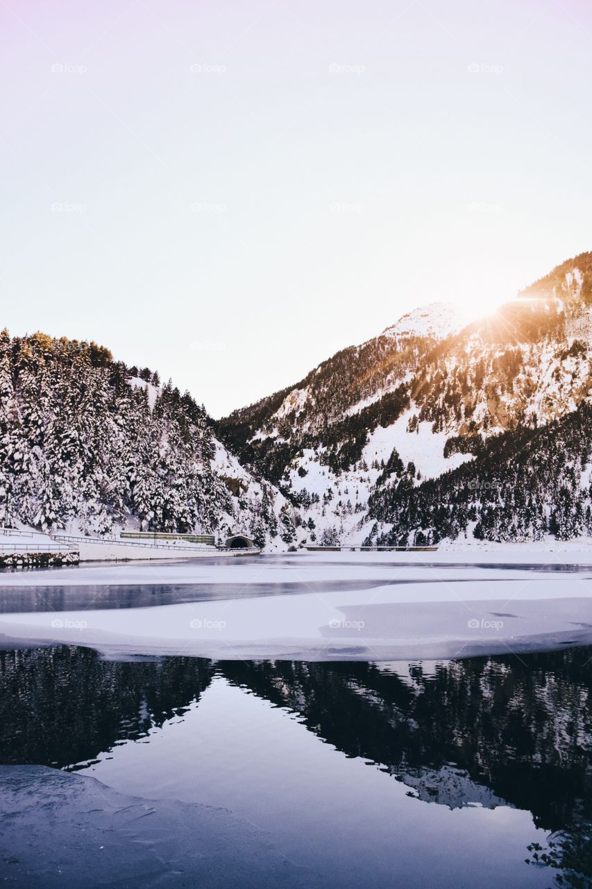 Snowy mountain reflected on frozen lake