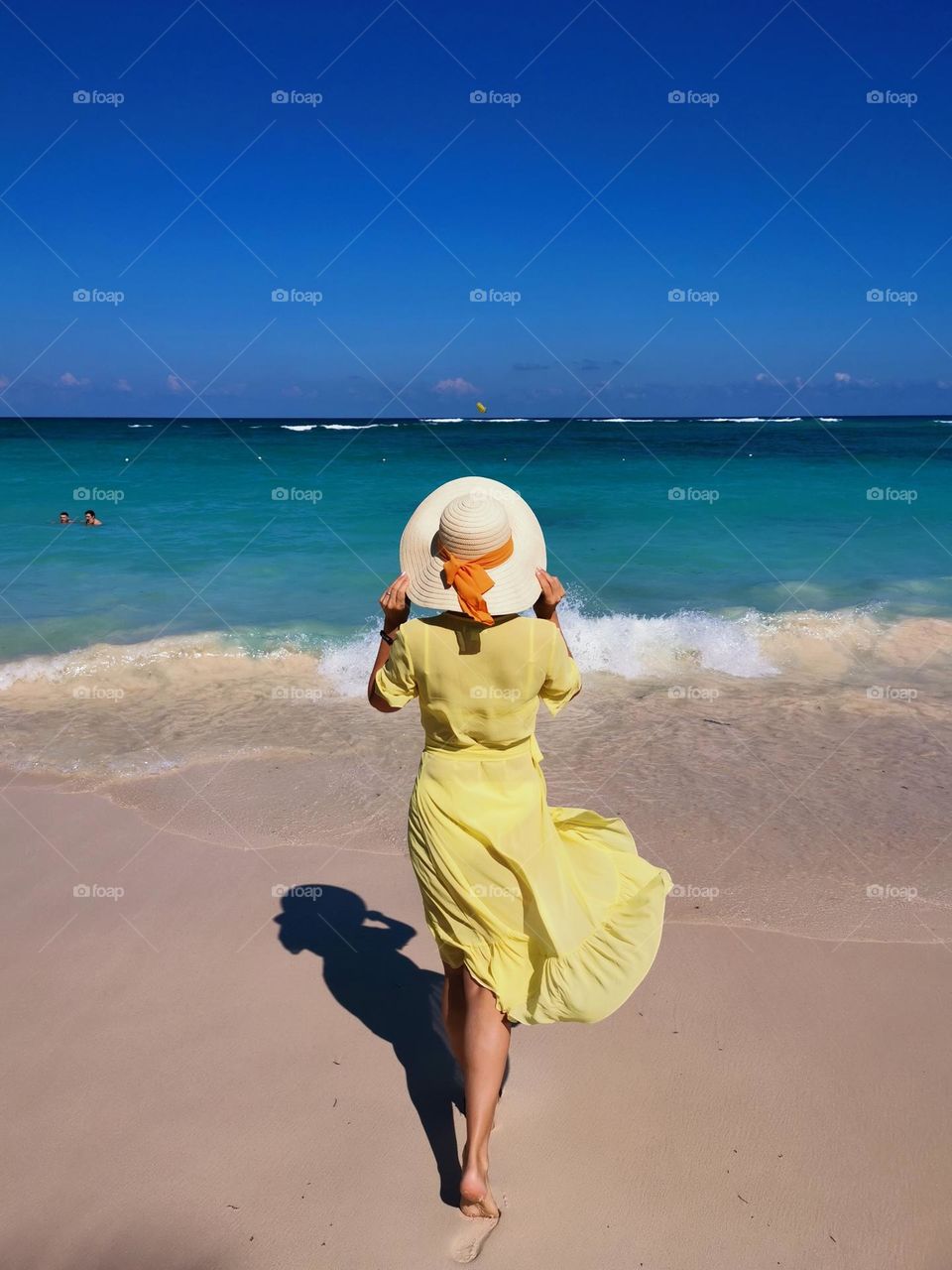 Holiday in Dominican Republic. Woman in a hat. Summertime. Yellow dress. On the beach.