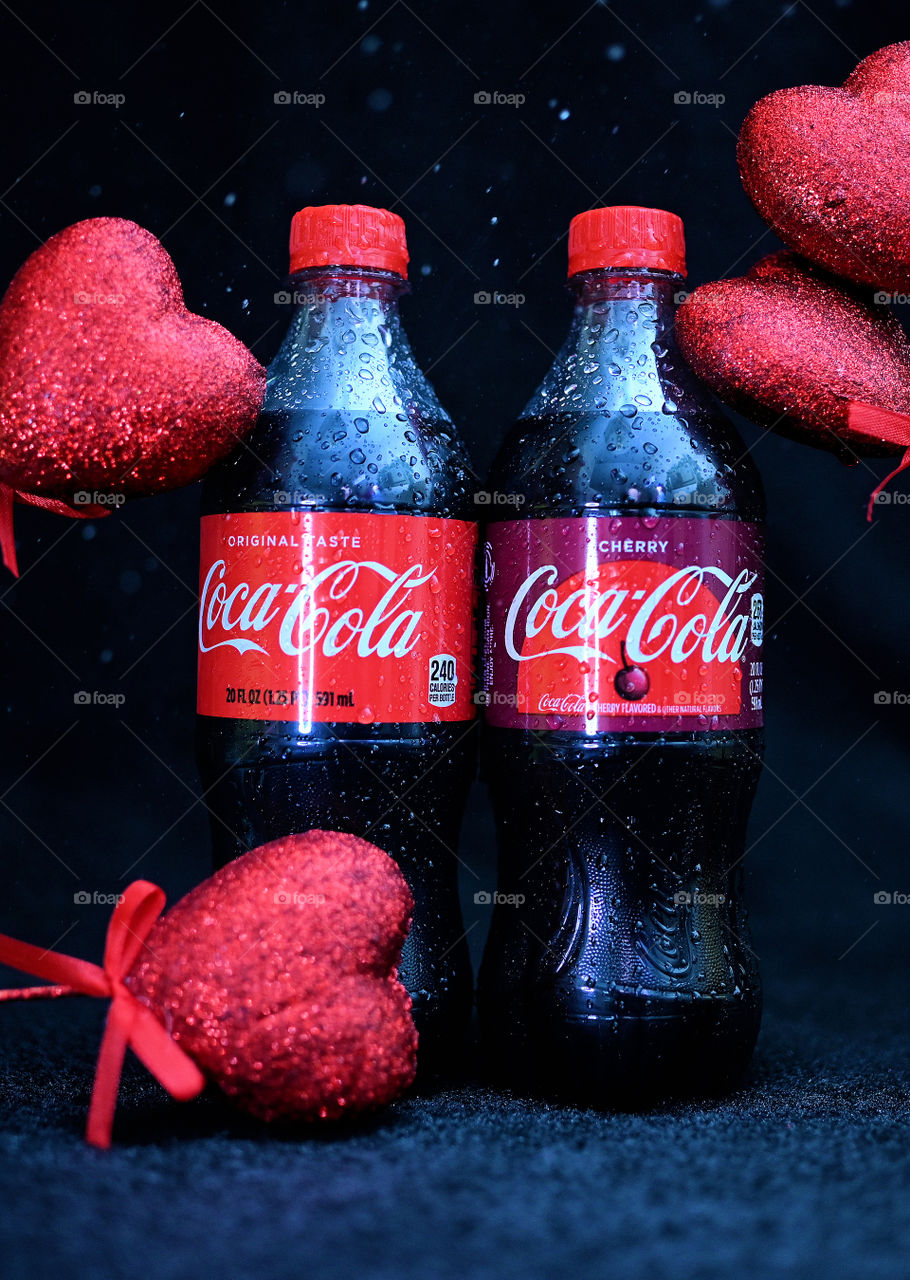 Close up shot of coke cola with valentine hearts in a black background in studio.