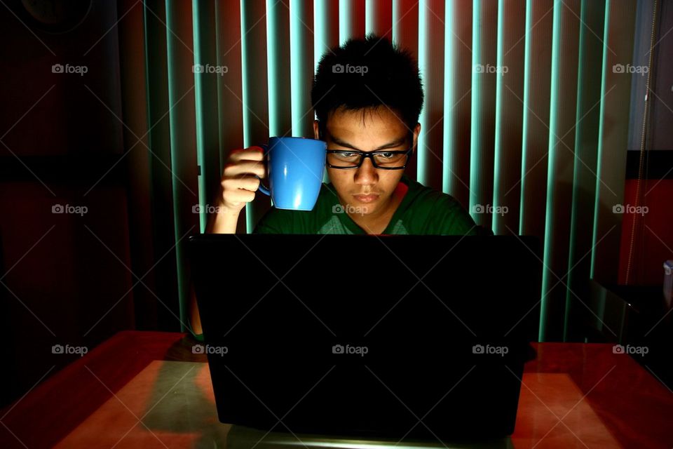 teenager working on a laptop computer and holding a blue coffee mug