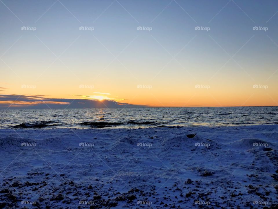 Snowy beach at Lake Michigan, sunset behind the clouds