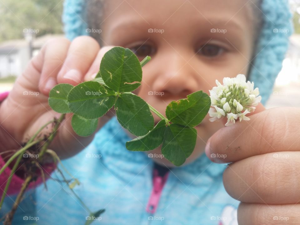 Little girl showing small white flower with plant