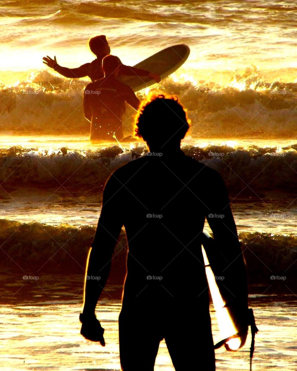 The Surfers. Three surfers getting ready to enjoy a late afternoon surf at a sun drenched San Diego beach