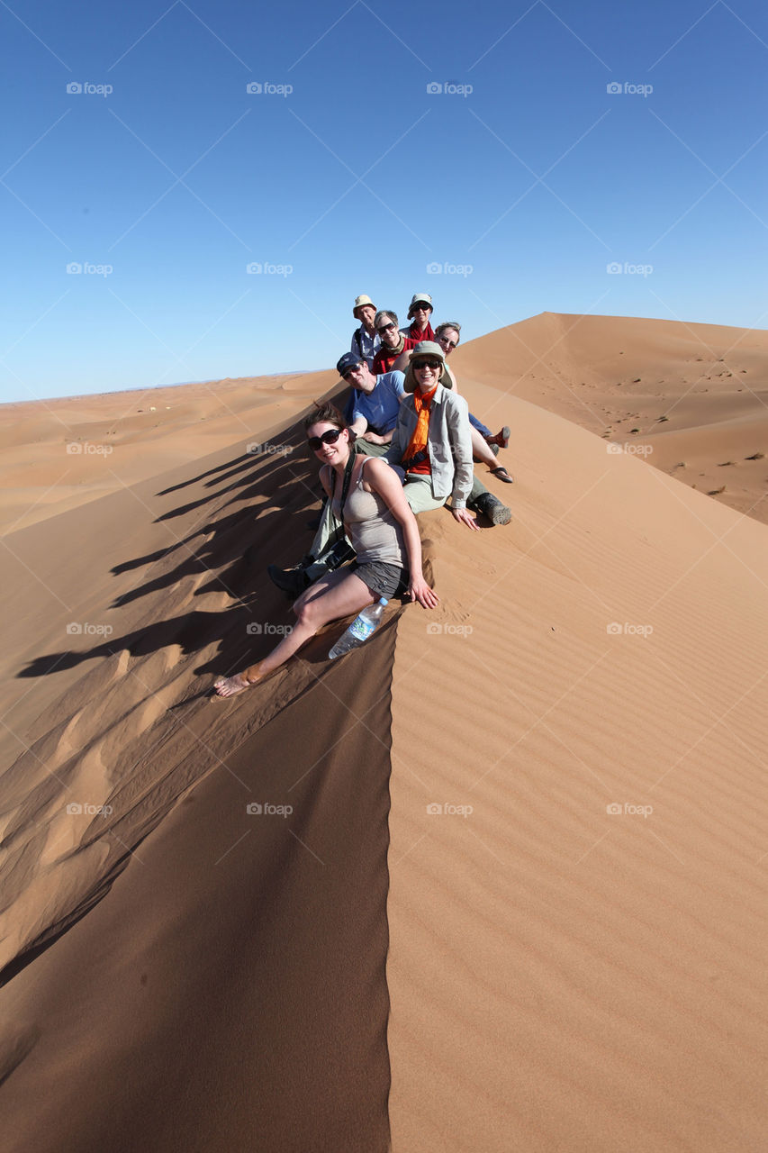 Tourists swatting atop a dune on the Moroccan Sahara