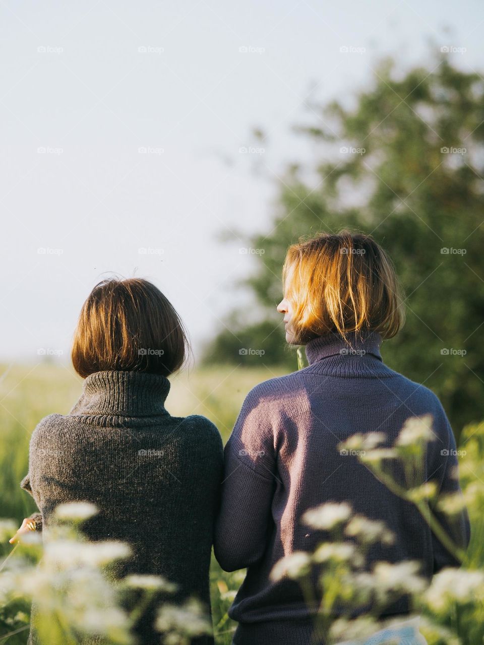 Two beautiful girlfriends in the field, back view