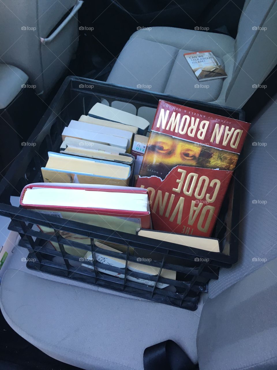 Books in a Box. Da Vinci Code by Dan Brown is shown upside down. The box is in a car. 