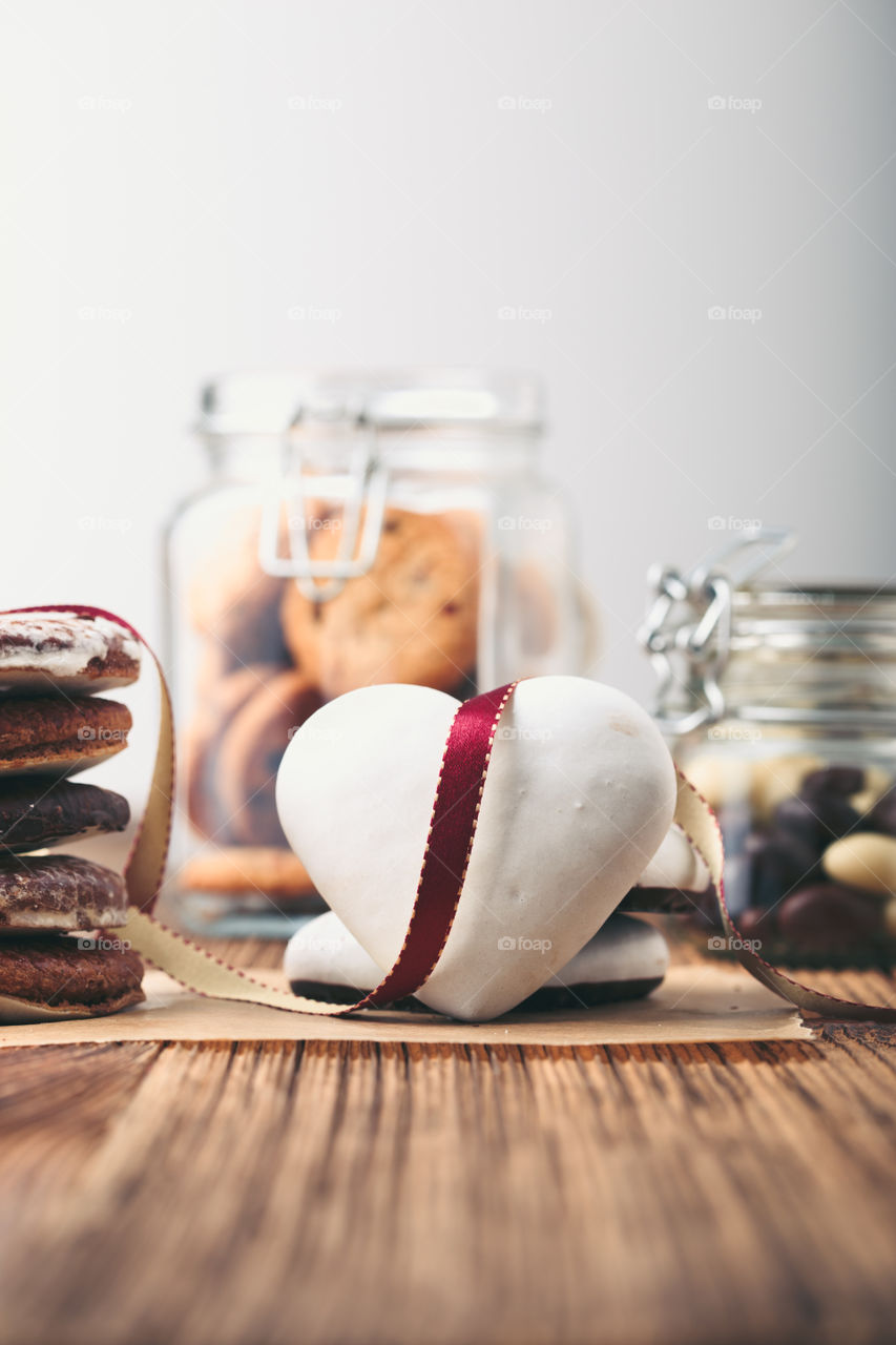Gingerbread cookies, candies, cakes, sweets in jars on wooden table