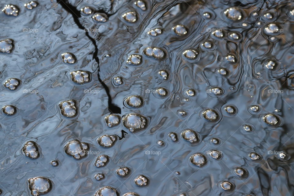 Bubbles  in the streaming water, close up view from above and surrounding reflecting inside them