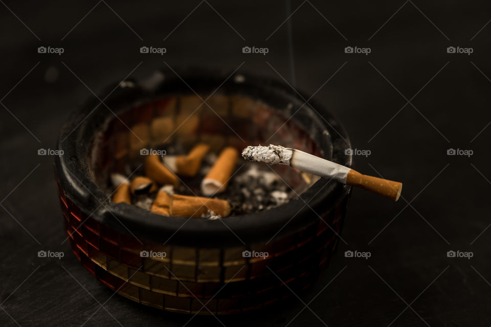 ashtray and smoldering cigarette - unhealthy addiction