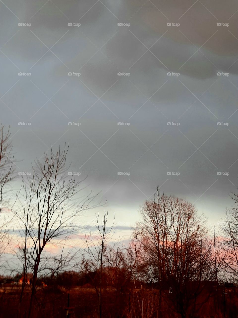 the last rays of the sun turn the landscape orange and dark clouds announce snow