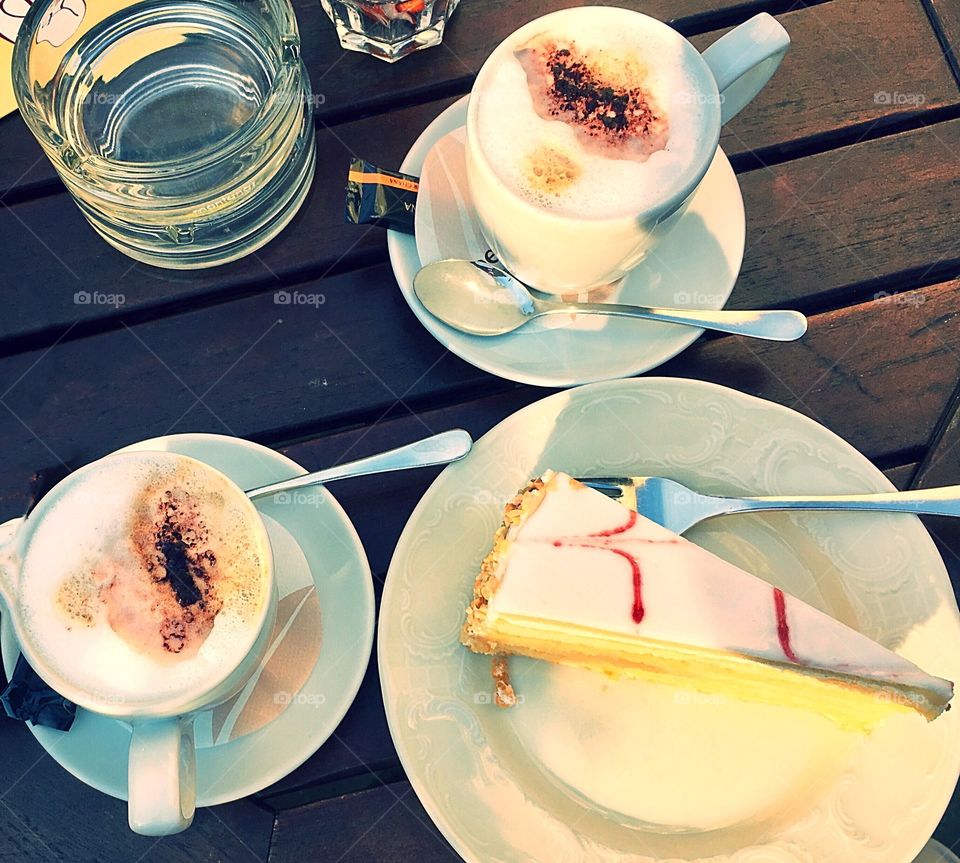 Two cups of cappuccino and lemon cake on a wooden table