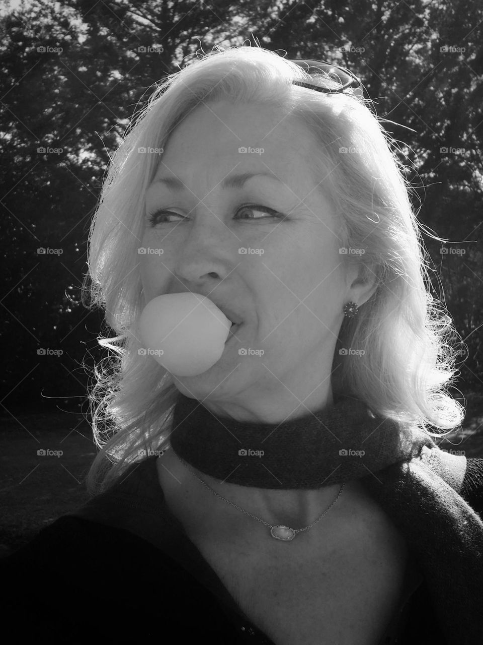 Black & white shotbof a woman blowing a bubble gum bubble outside