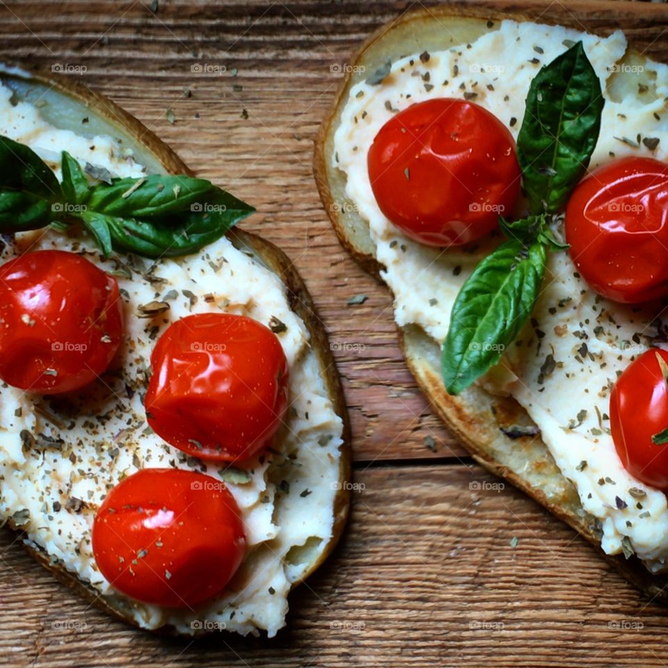 Tomato, basil and vegan cheese on roasted potato slices  