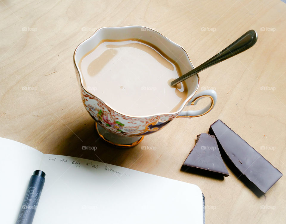 Milky hot drink, chocolate and some notes on wooden surface