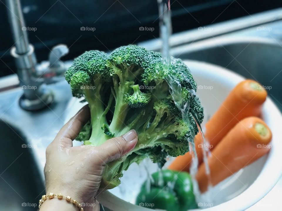 Washing broccoli carrots and capsicum under running water