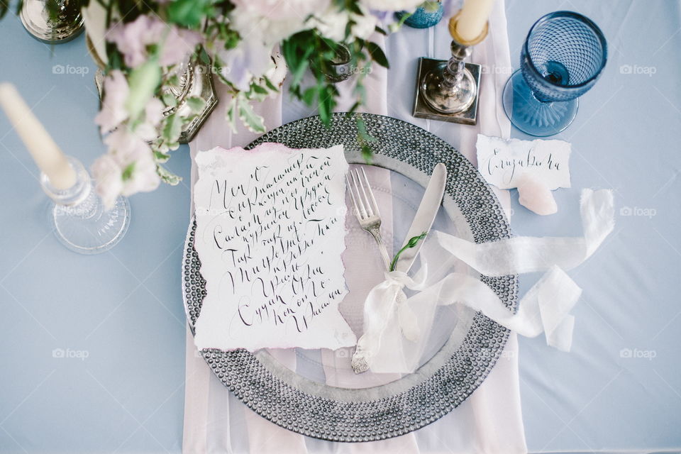 Graphic arts of beautiful wedding calligraphy cards and silver plate with cutlery on festive wedding table. 